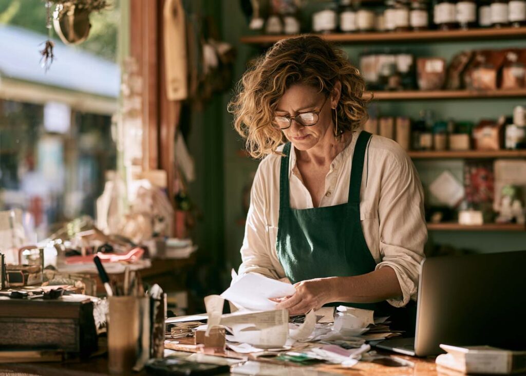 Small business owner going through paperwork behind the counter of her shop