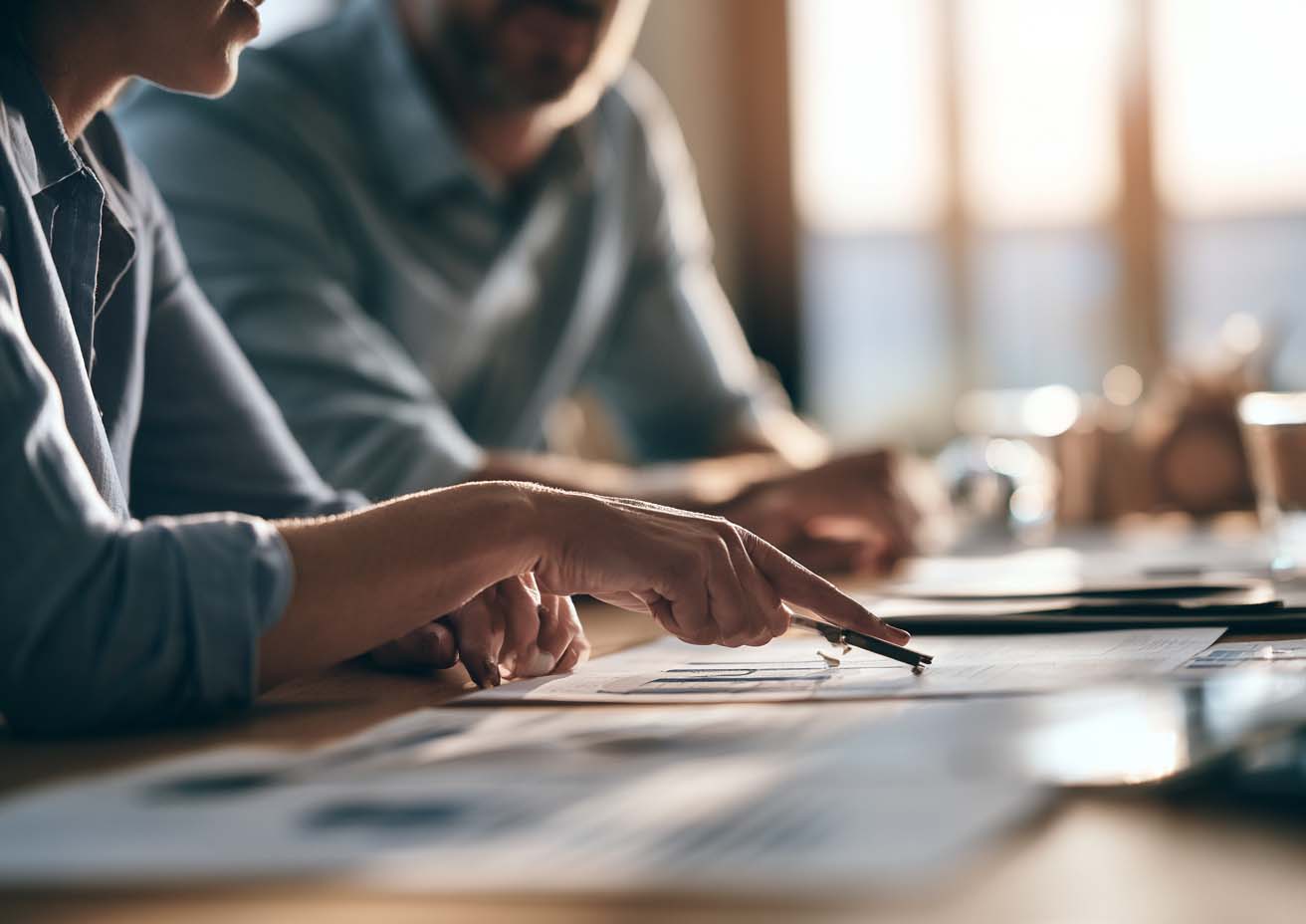 Two people reviewing printed financial reports across a desk