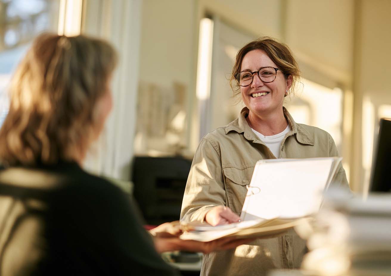 Bookkeeper smiling with an open folder while meeting a client