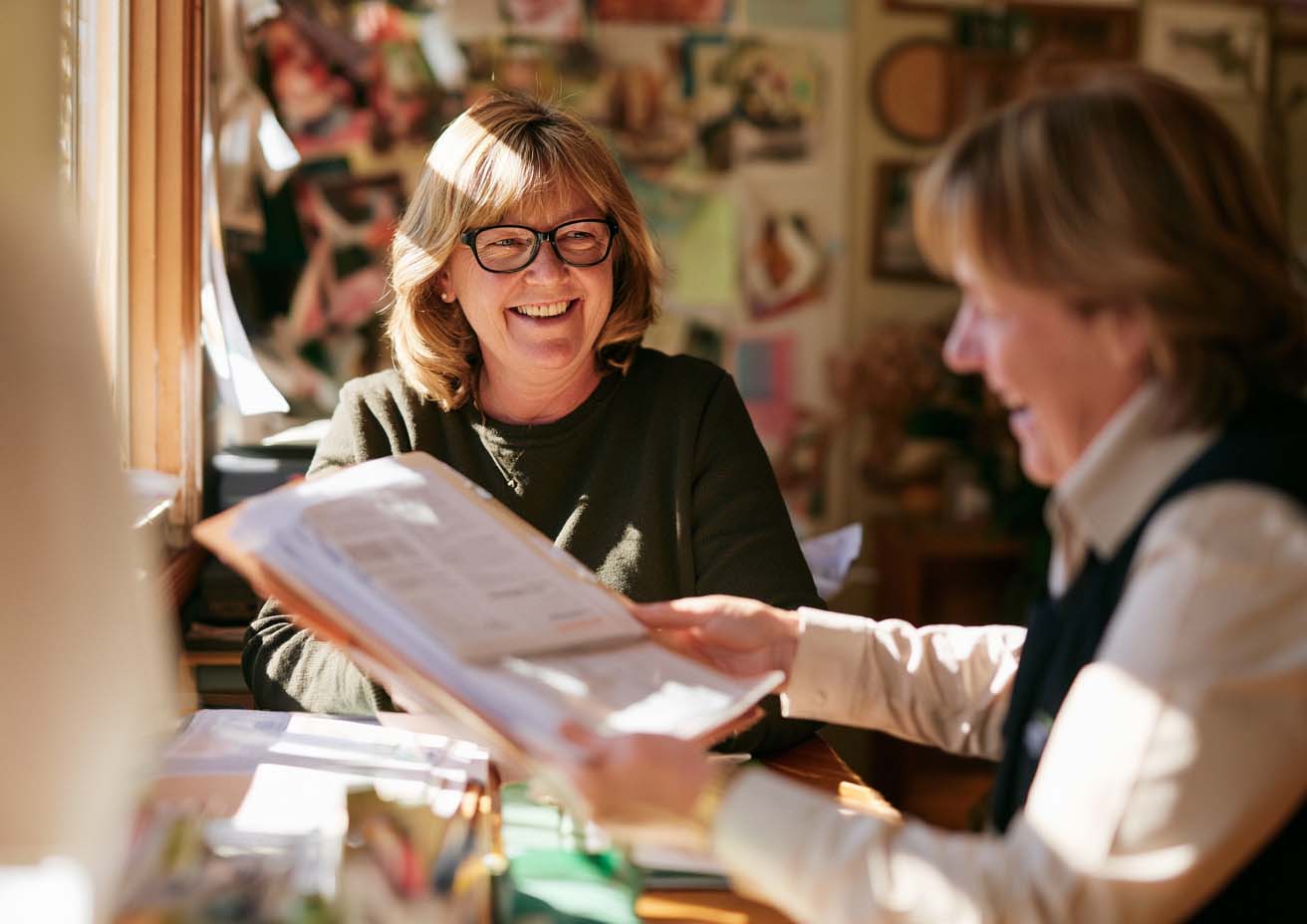 Two women laughing while going through paperwork together