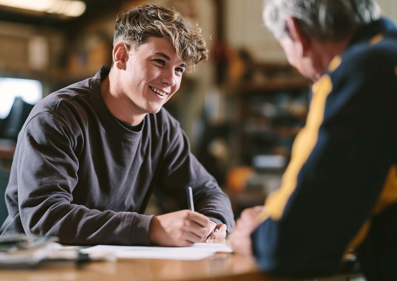 Young apprentice filling in paperwork with an older tradesman in a workshop