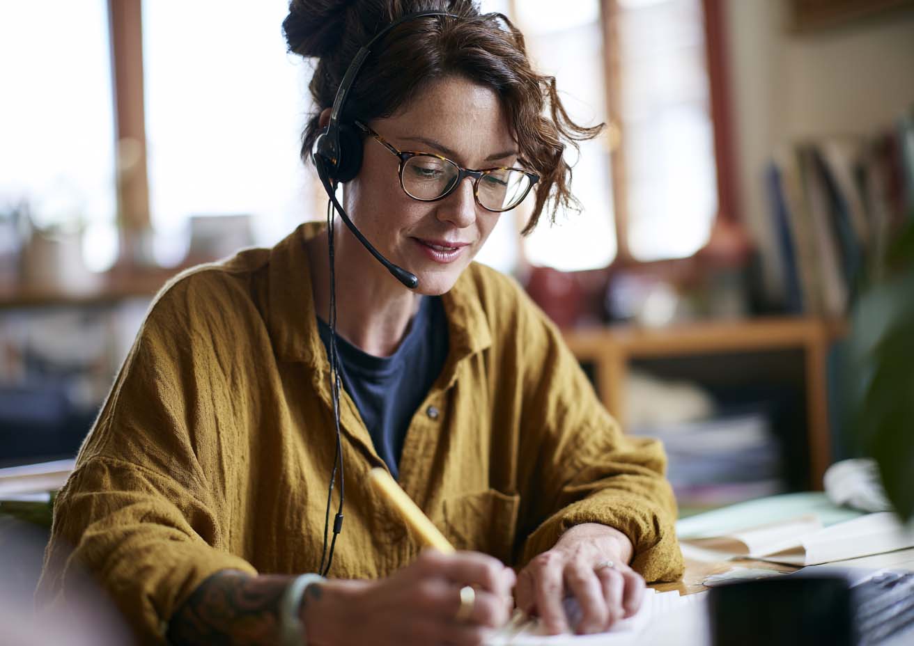 Bookkeeper wearing a headset writing notes at a desk